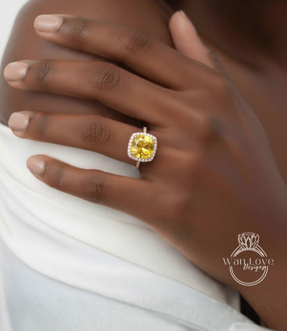 A close-up of a person's hand wearing a yellow diamond ring on the ring finger.