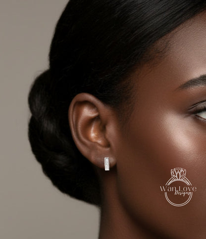 A close-up of a woman's ear with a small rectangular earring, showcasing the ear and the earring itself.