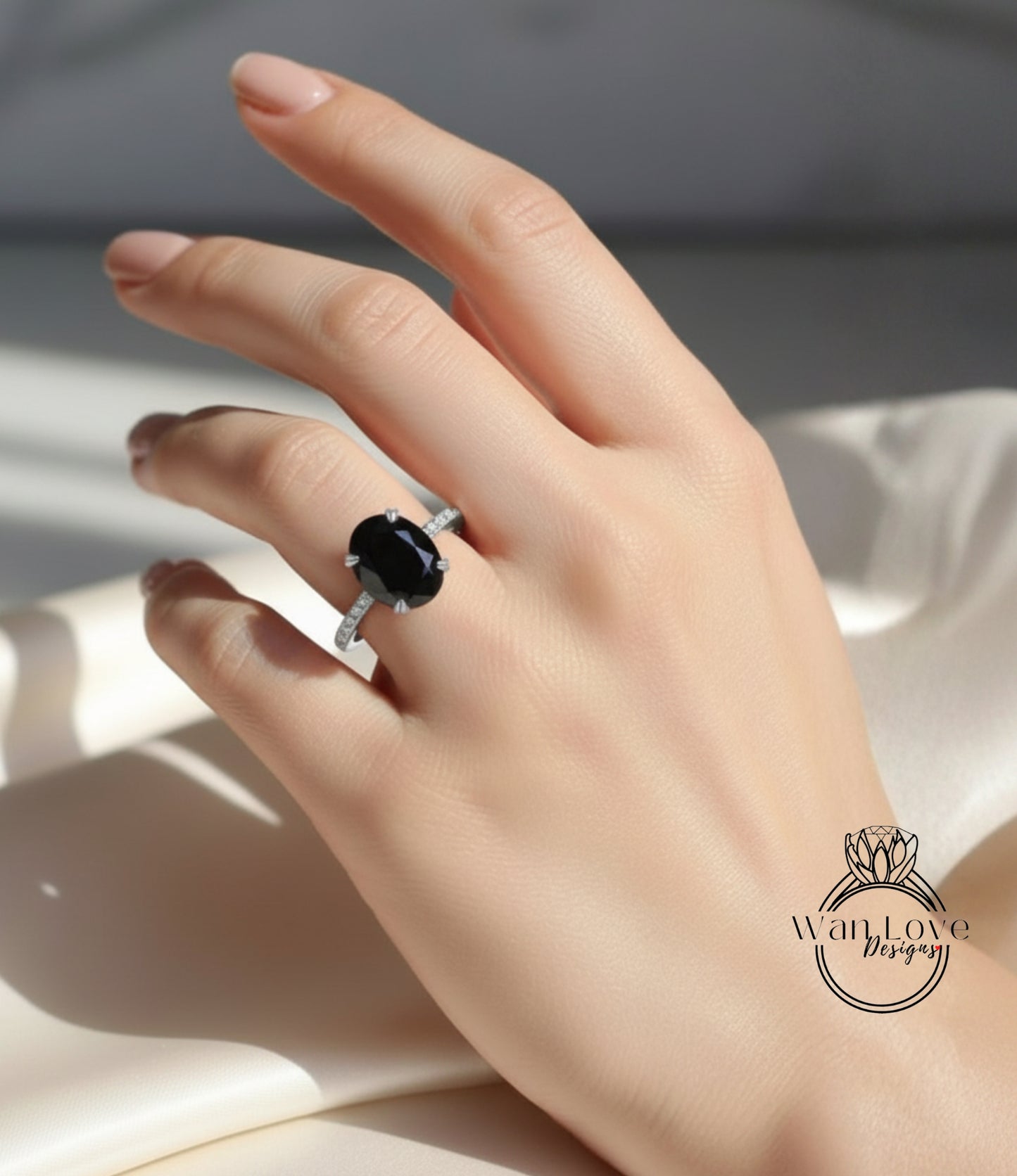 A close-up of a hand wearing a ring with a large oval-shaped black gemstone.