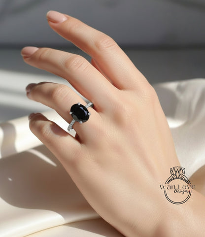 A close-up of a hand wearing a ring with a large oval-shaped black gemstone.