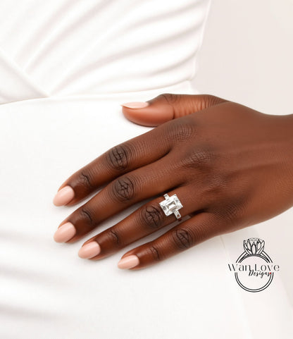 A close-up of a hand wearing a diamond engagement ring, with a white dress visible in the background.