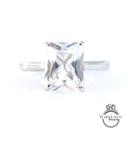 A close-up image of a diamond ring with a large, clear gemstone set in a silver band.