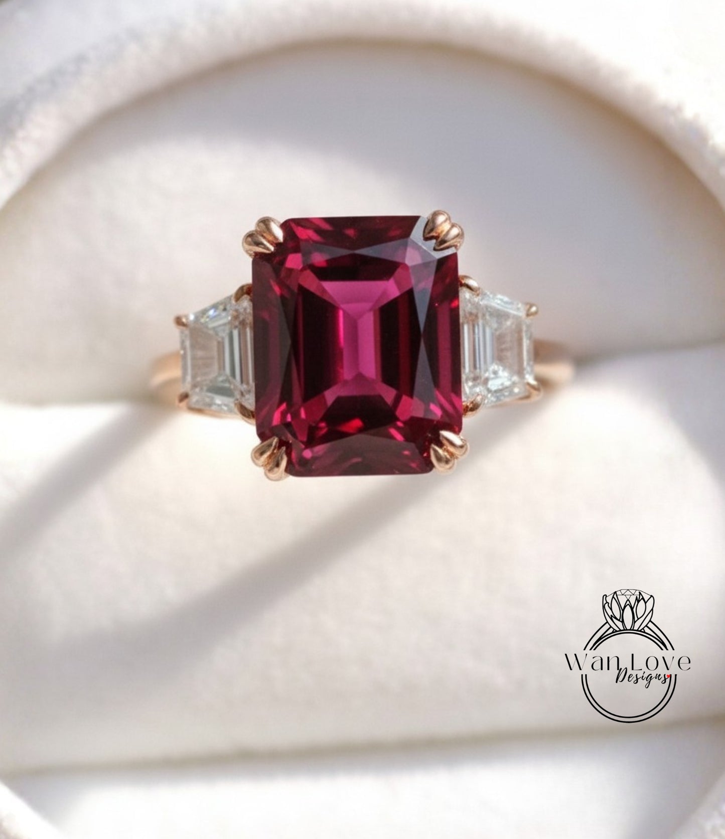 A close-up image of a gold ring with a large, deep red gemstone, possibly a garnet, set in the center.