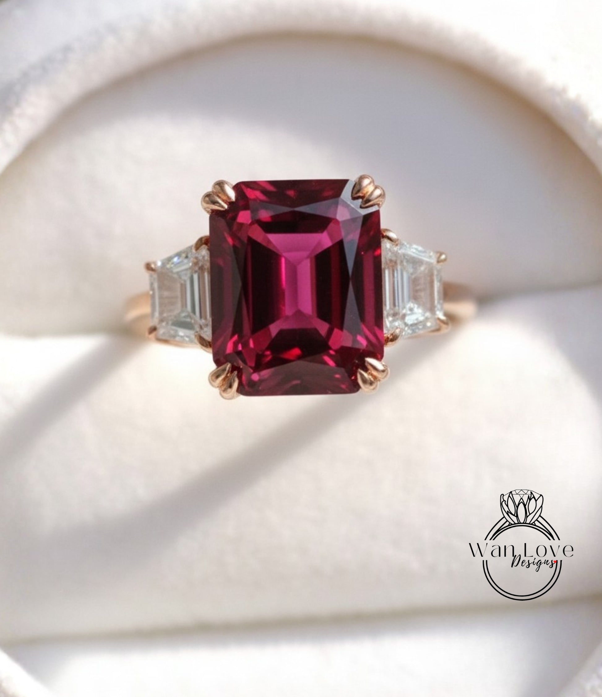 A close-up image of a gold ring with a large, deep red gemstone, possibly a garnet, set in the center.