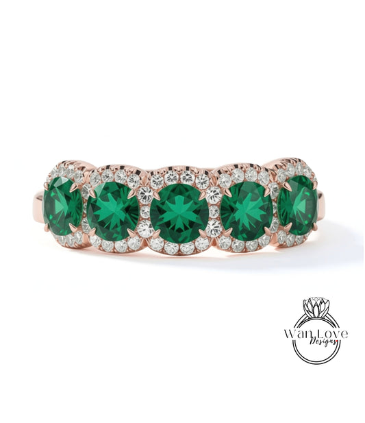 A ring with a row of green gemstones set in a rose gold band, with small diamonds around the edges.