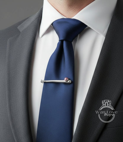 A close-up of a man's neck and chest wearing a gray suit jacket, a white shirt, and a blue tie with a pin on the lapel.