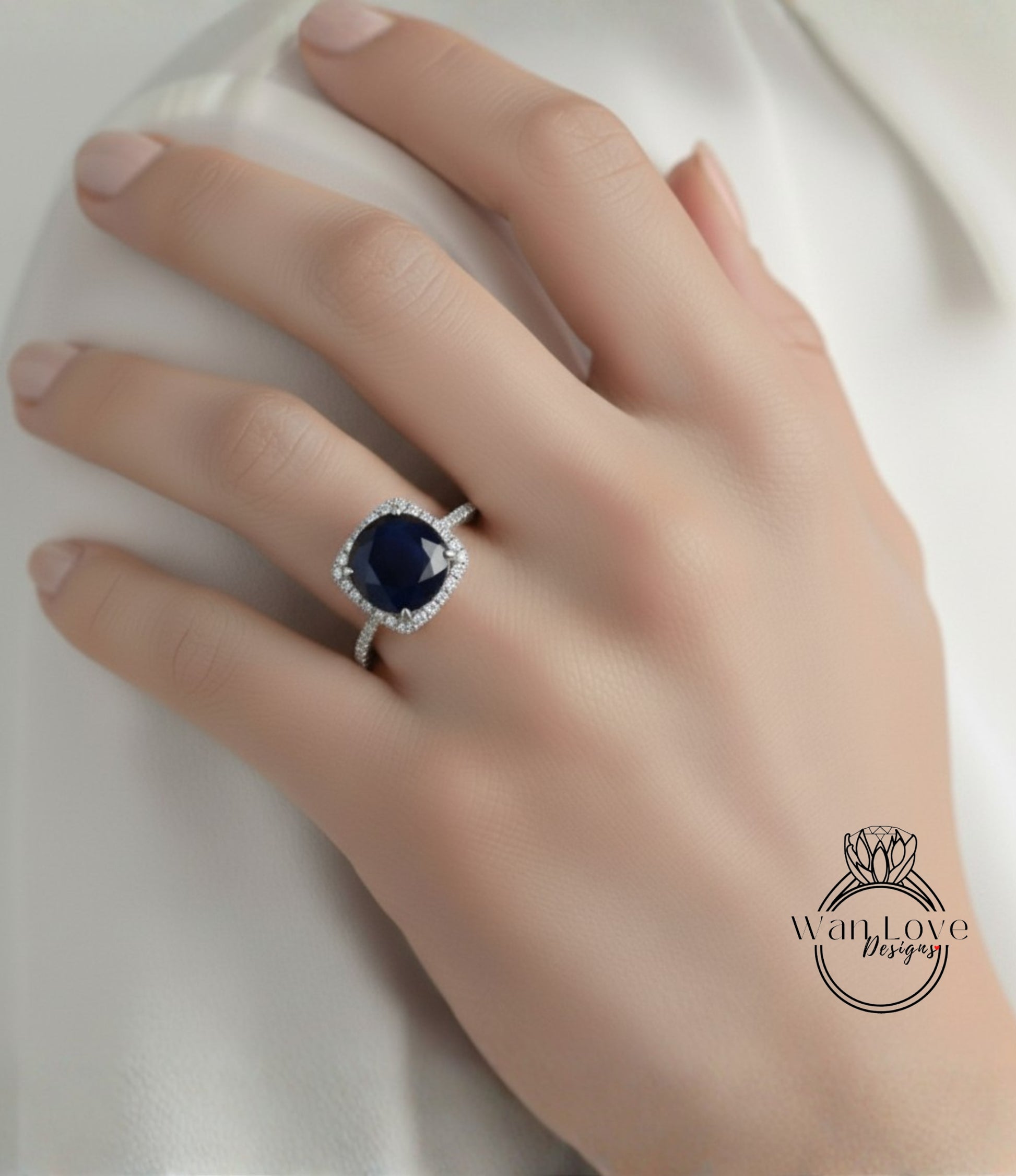 A close-up of a hand wearing a diamond ring with a large blue gemstone.