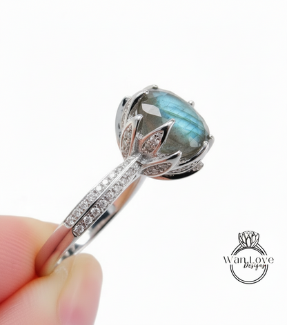 A close-up image of a silver ring with a large blue gemstone, possibly a diamond, set in a decorative floral design.
