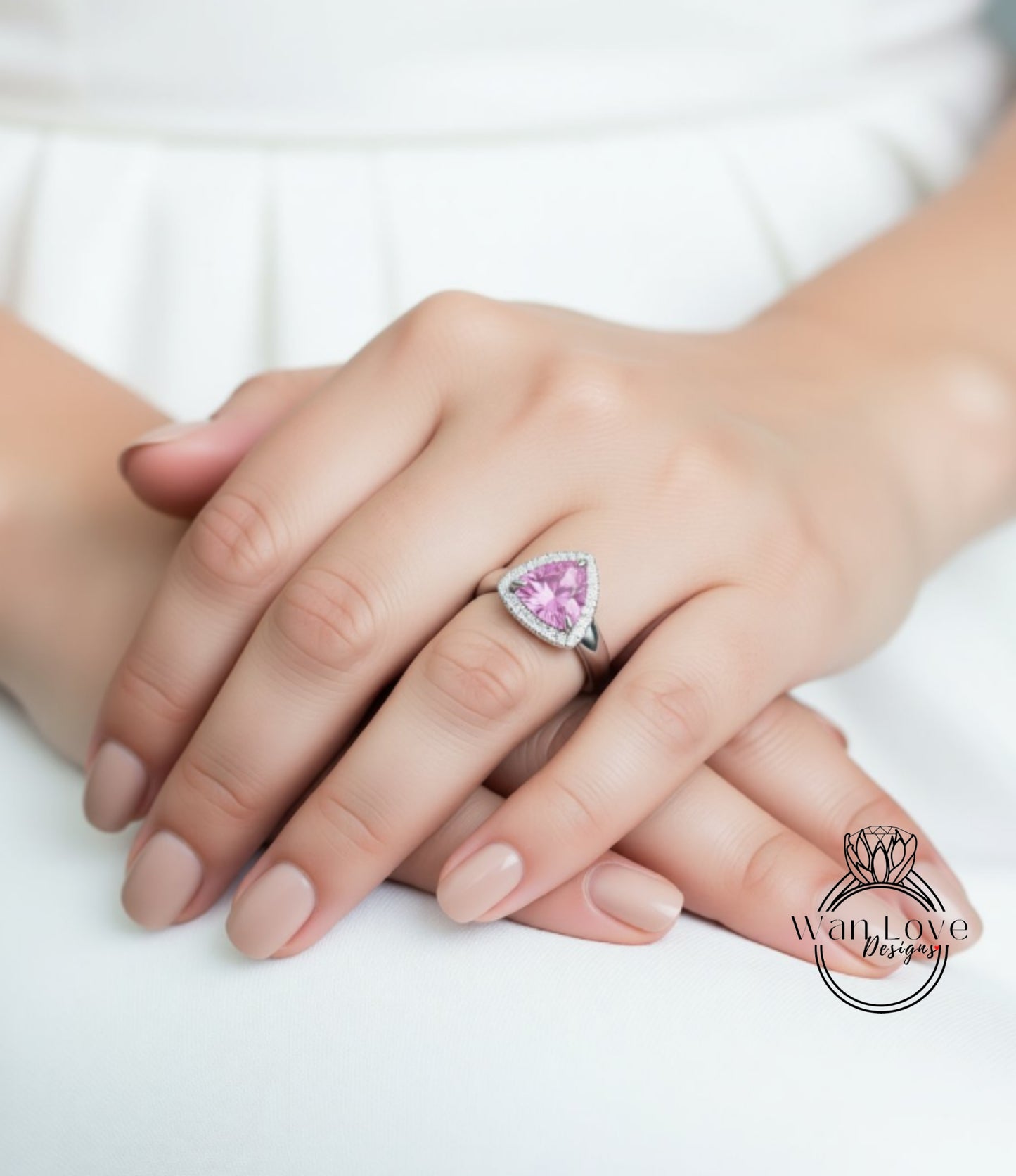 A close-up of a person's hand wearing a ring with a pink gemstone.