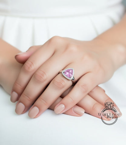 A close-up of a person's hand wearing a ring with a pink gemstone.