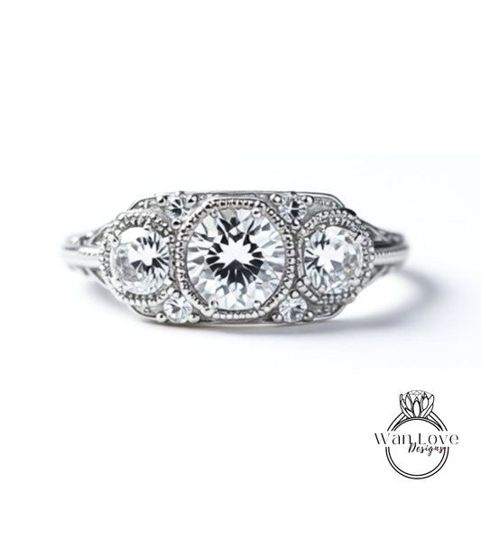 A close-up view of a diamond engagement ring with three large, clear gemstones set in a decorative metal band.