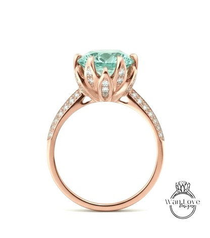 A rose gold ring with a large, light blue gemstone set in the center, surrounded by smaller diamonds.