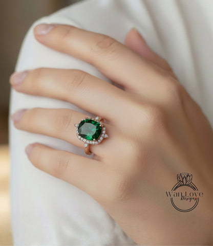 A close-up of a person's hand wearing a large, green gemstone ring with a halo of smaller diamonds around it.
