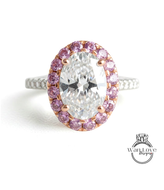 A large oval-shaped diamond ring with a halo of smaller diamonds around the center stone, set in a silver band with pink gemstones.