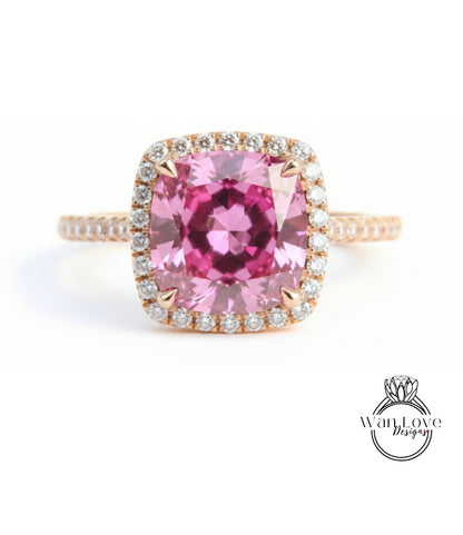 A pink gemstone engagement ring with a halo of smaller diamonds around the center stone.