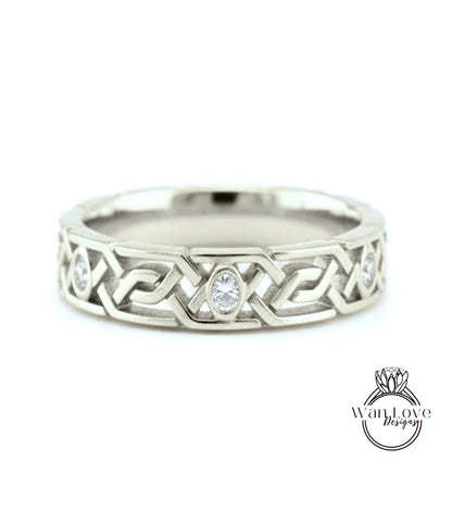 A silver wedding band with a Celtic knot design and a central oval-shaped diamond.
