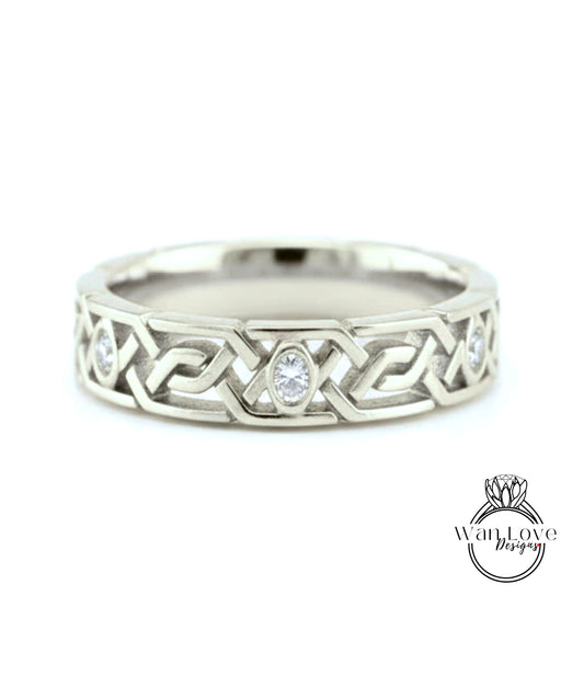 A silver wedding band with a Celtic knot design and a central oval-shaped diamond.