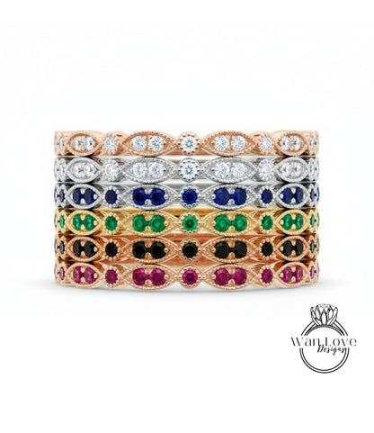 A stack of rings with various colored gemstones, including diamonds and colored gemstones, set in a gold or silver band.