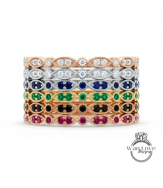 A stack of rings with various colored gemstones, including diamonds and colored gemstones, set in a gold or silver band.
