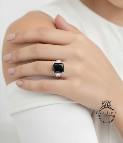 A close-up of a person's hand wearing a large, black gemstone ring on the ring finger.