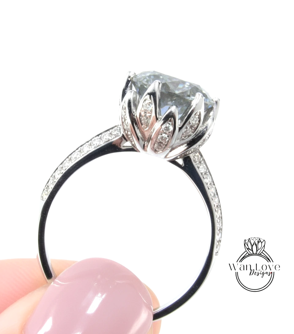 A close-up of a person's hand holding a silver ring with a large, clear gemstone, likely a diamond, on the ring.