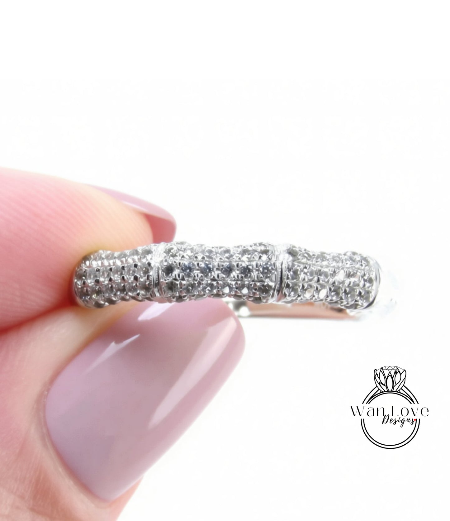 A close-up of a person's hand holding a ring with a sparkling diamond band.