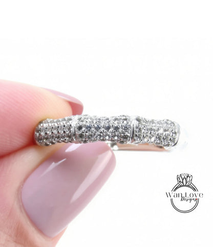 A close-up of a person's hand holding a ring with a sparkling diamond band.