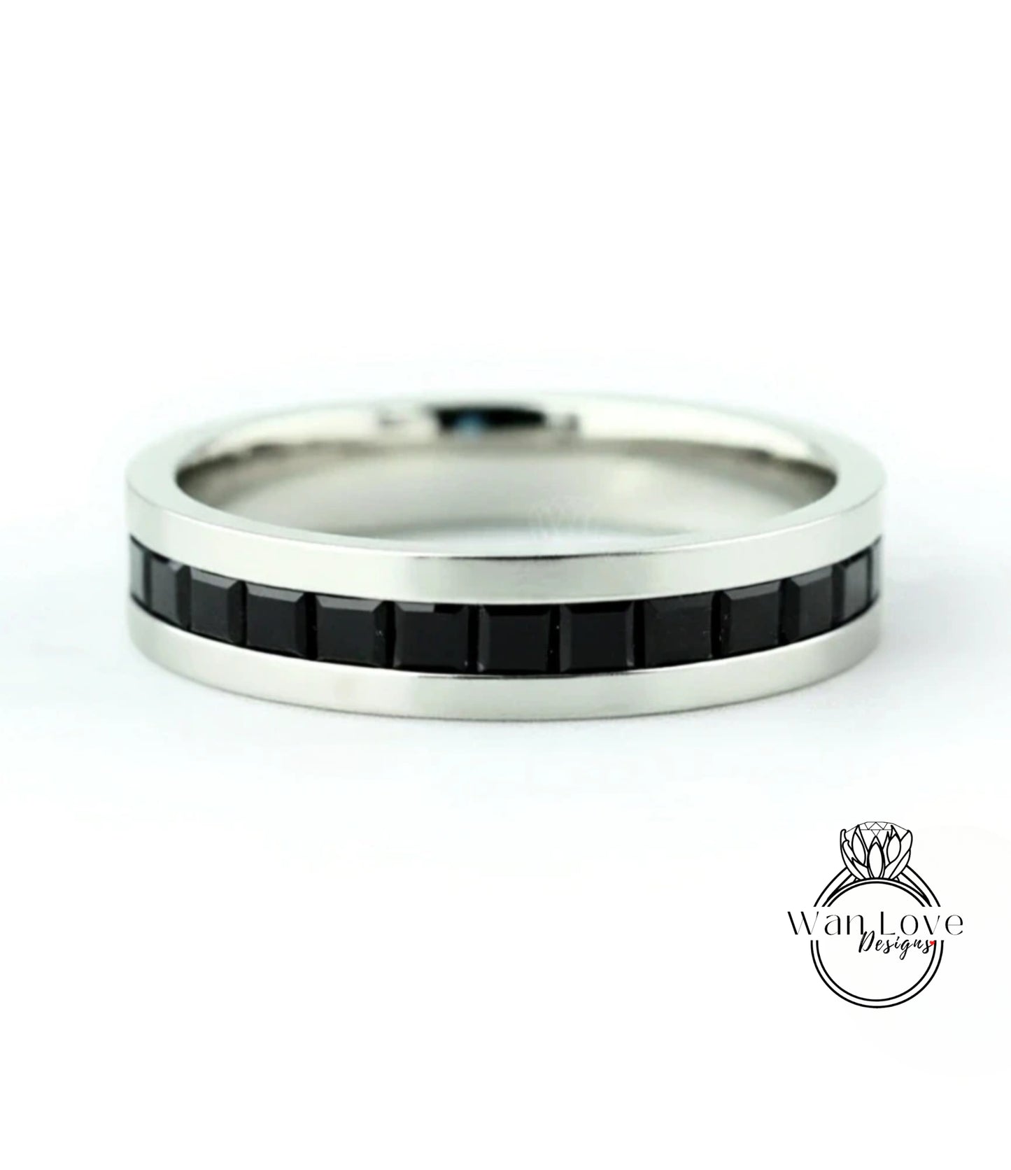 A silver ring with a row of black gemstones along the band.