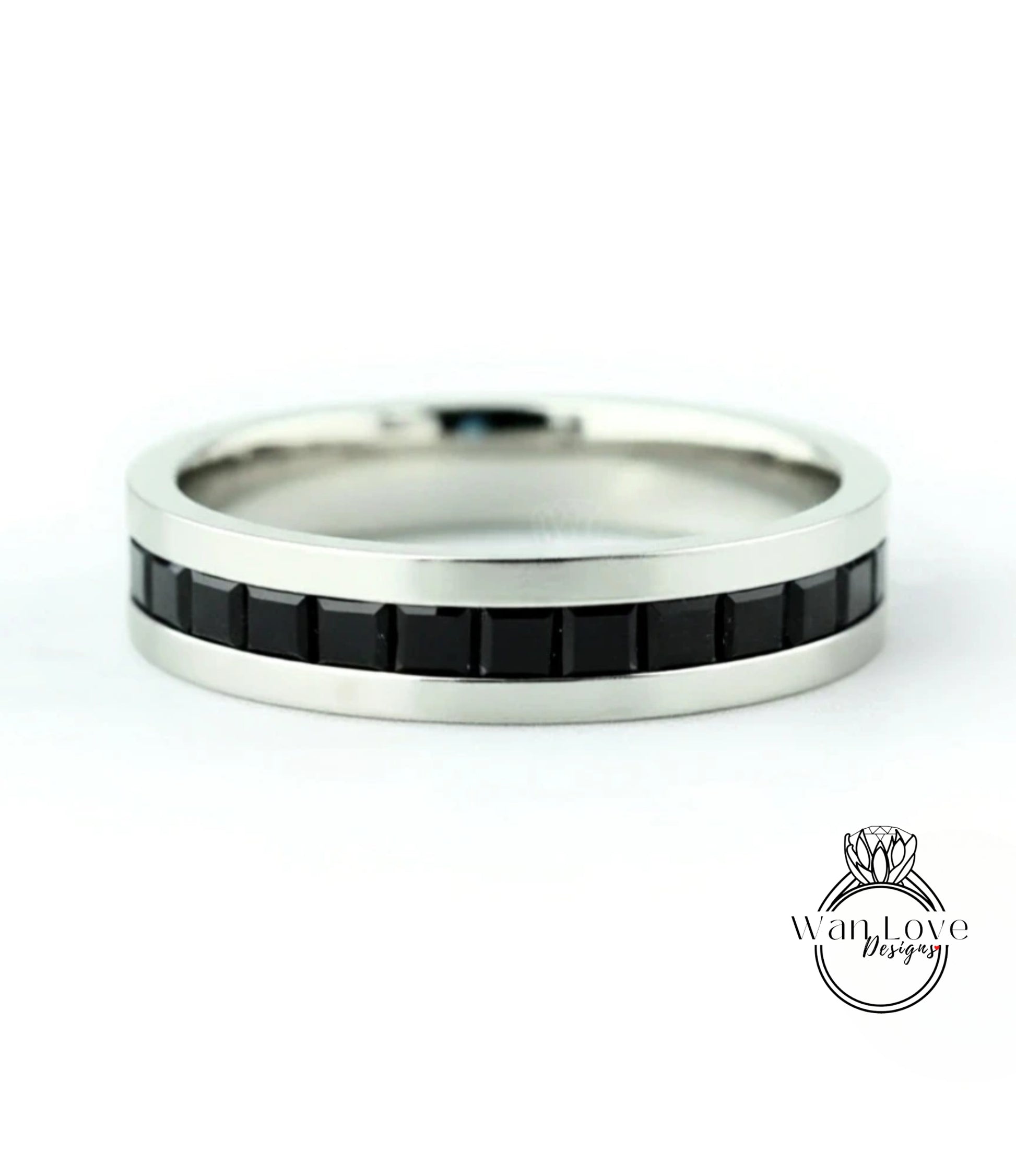 A silver ring with a row of black gemstones along the band.