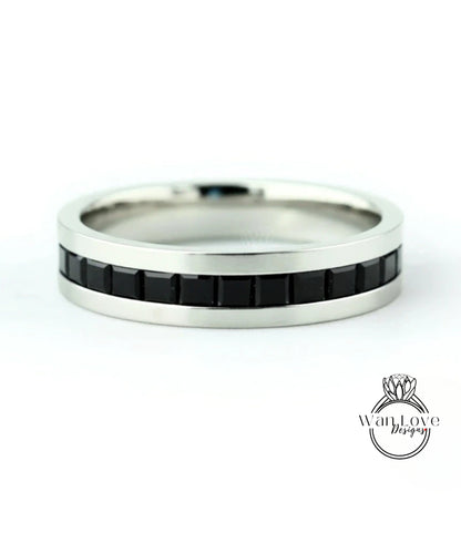 A silver ring with a row of black gemstones along the band.