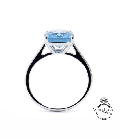 A silver ring with a large blue gemstone, likely a diamond, set in the center.