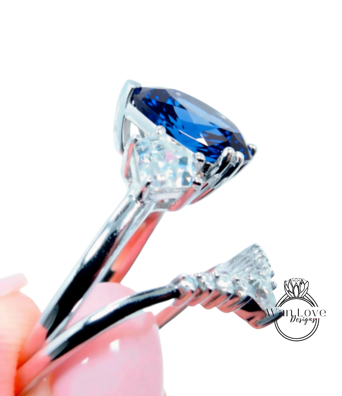 A close-up view of a silver ring with a large blue gemstone, held in a hand against a white background.