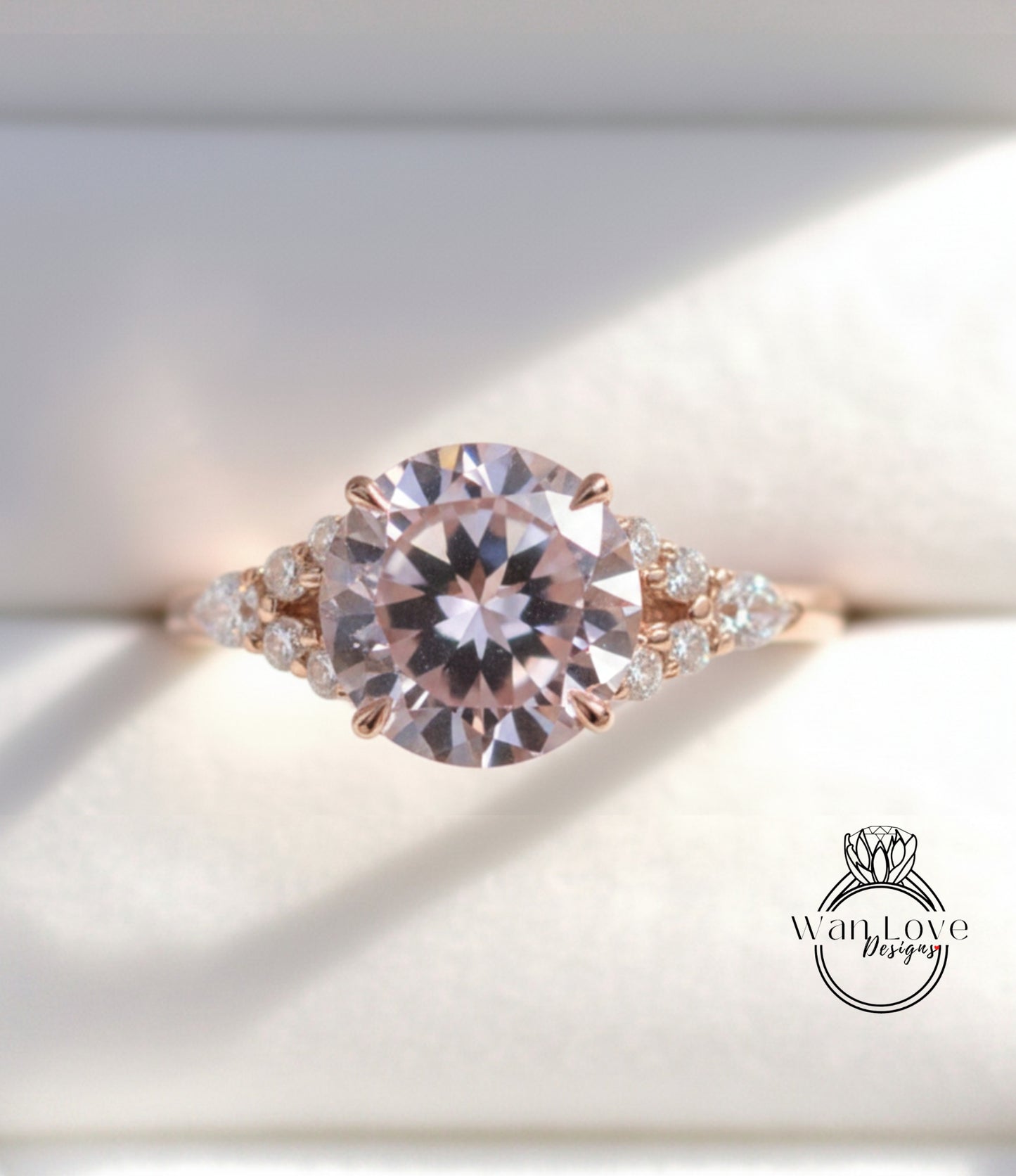 A close-up image of a beautiful pink diamond engagement ring with a large central diamond surrounded by smaller diamonds on either side.