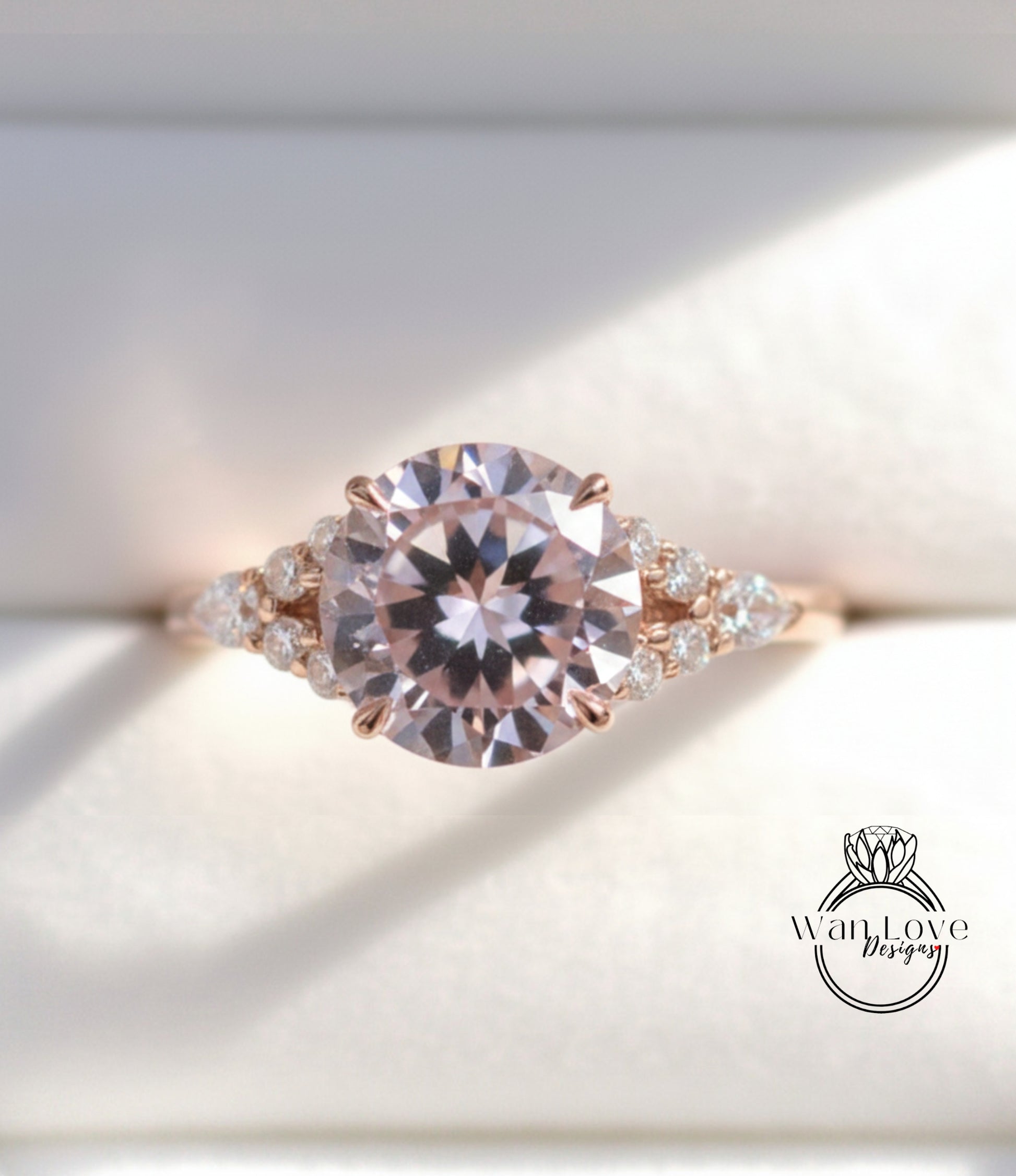 A close-up image of a beautiful pink diamond engagement ring with a large central diamond surrounded by smaller diamonds on either side.