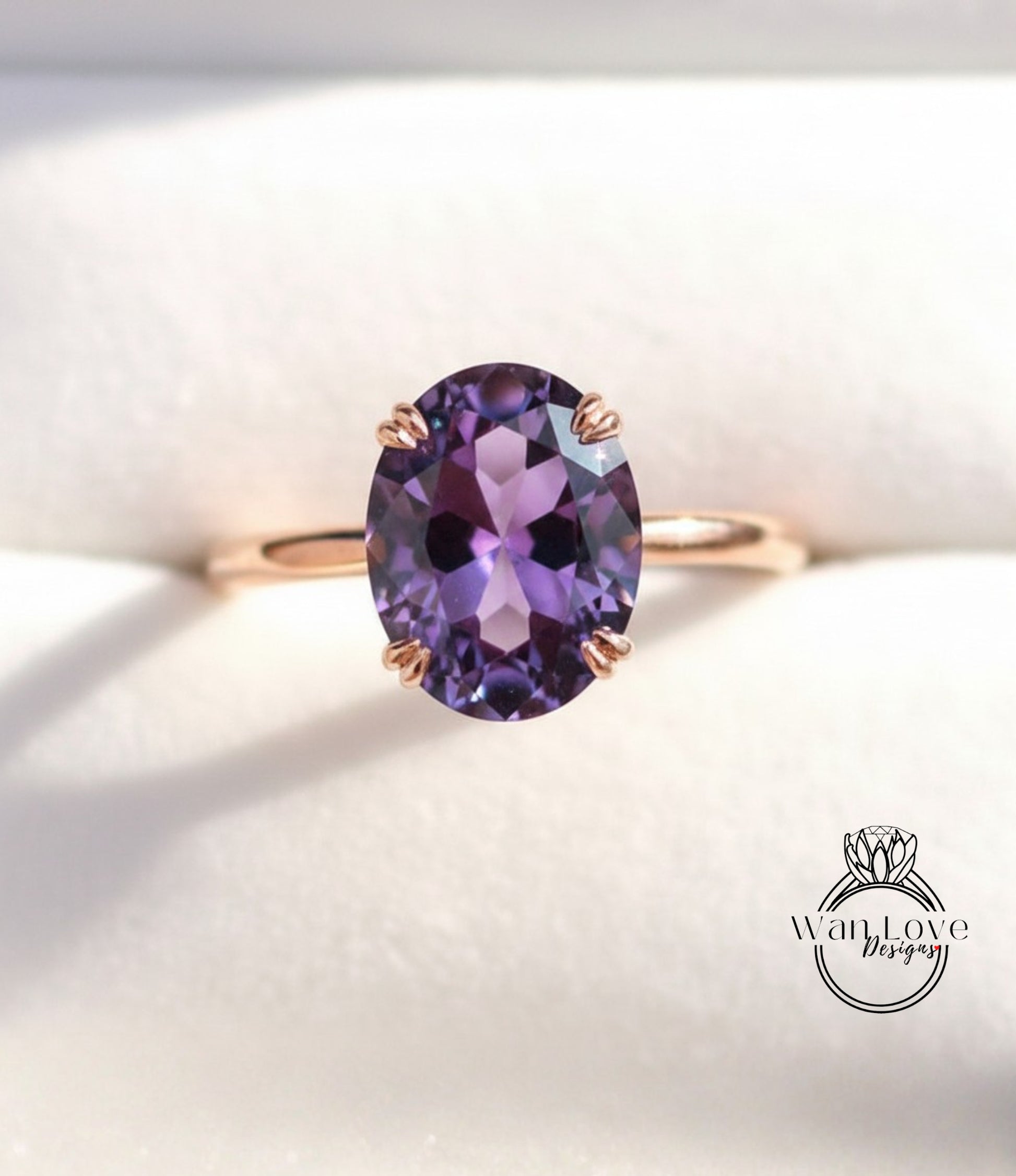 A close-up image of a gold ring with a large oval-shaped purple gemstone, likely an amethyst, set in the center of the band.