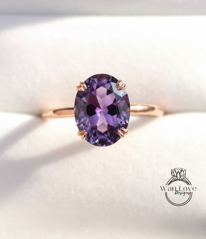 A close-up image of a gold ring with a large oval-shaped purple gemstone, likely an amethyst, set in the center of the band.