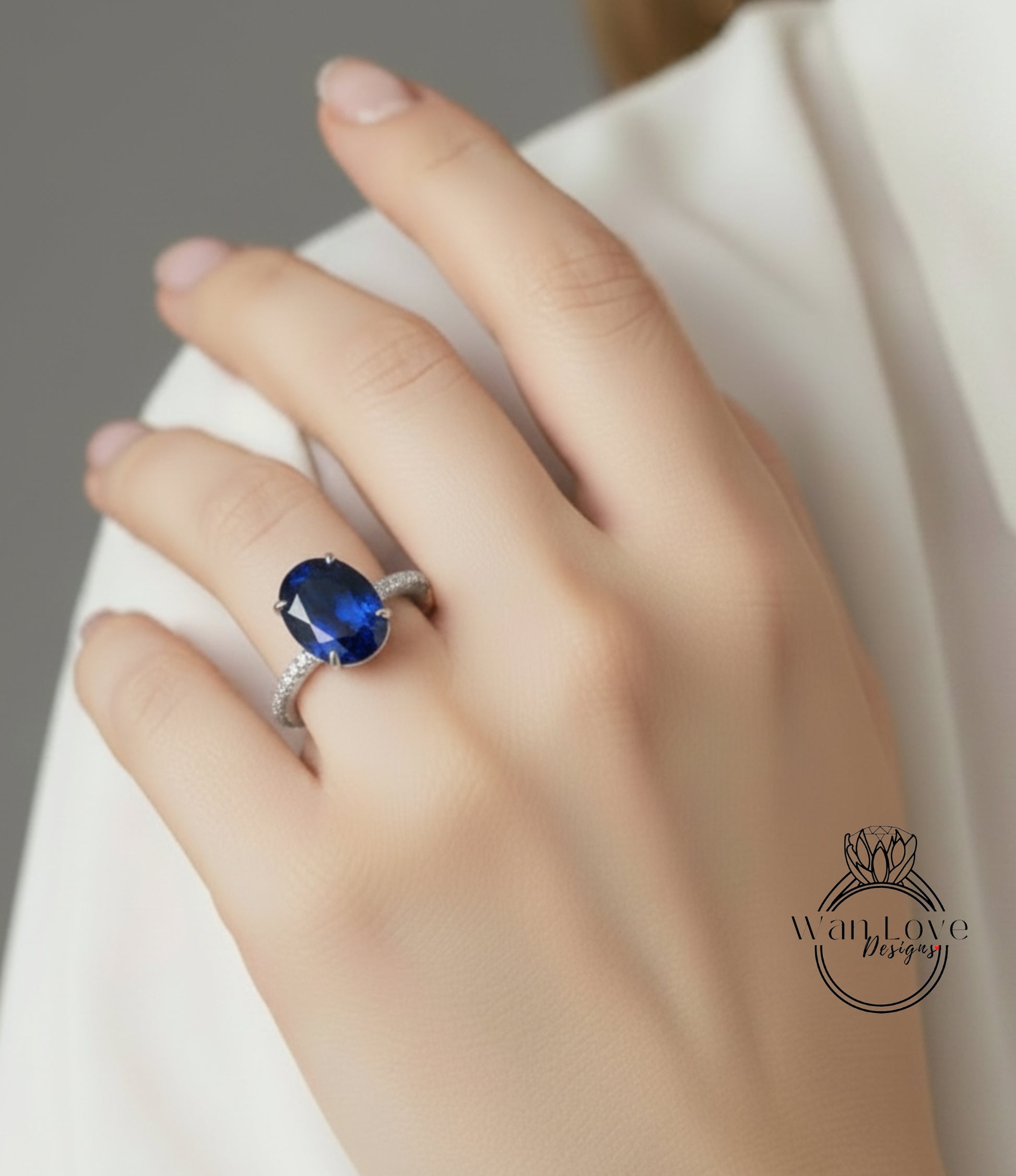 A close-up of a hand wearing a ring with a large blue gemstone, likely a sapphire.