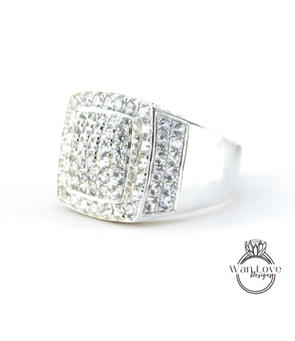 A silver ring with a large diamond-encrusted square cut gemstone.