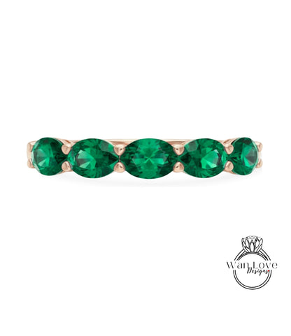 A gold ring with a row of green gemstones, likely diamonds, set in the center.