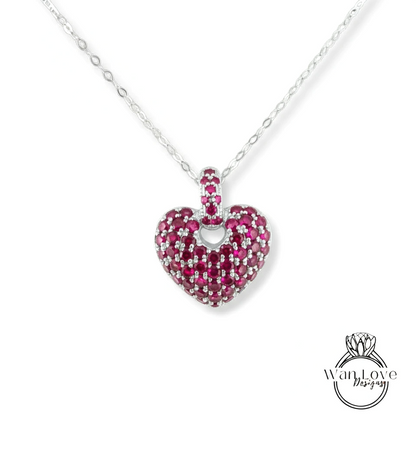 A heart-shaped pendant necklace with a large, sparkling red gemstone in the center.