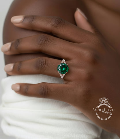 A close-up of a person's hand wearing a ring with a large, green gemstone.