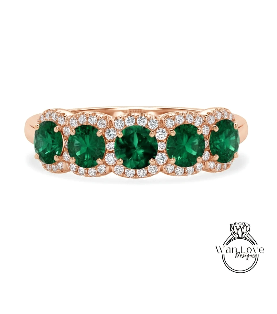 A rose gold ring with a row of green gemstones, including diamonds, set in the center.