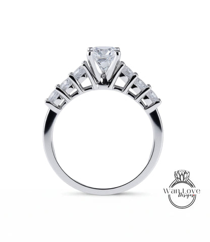 A close-up view of a silver engagement ring with a large central diamond surrounded by smaller diamonds arranged in a fan-like design on the band.
