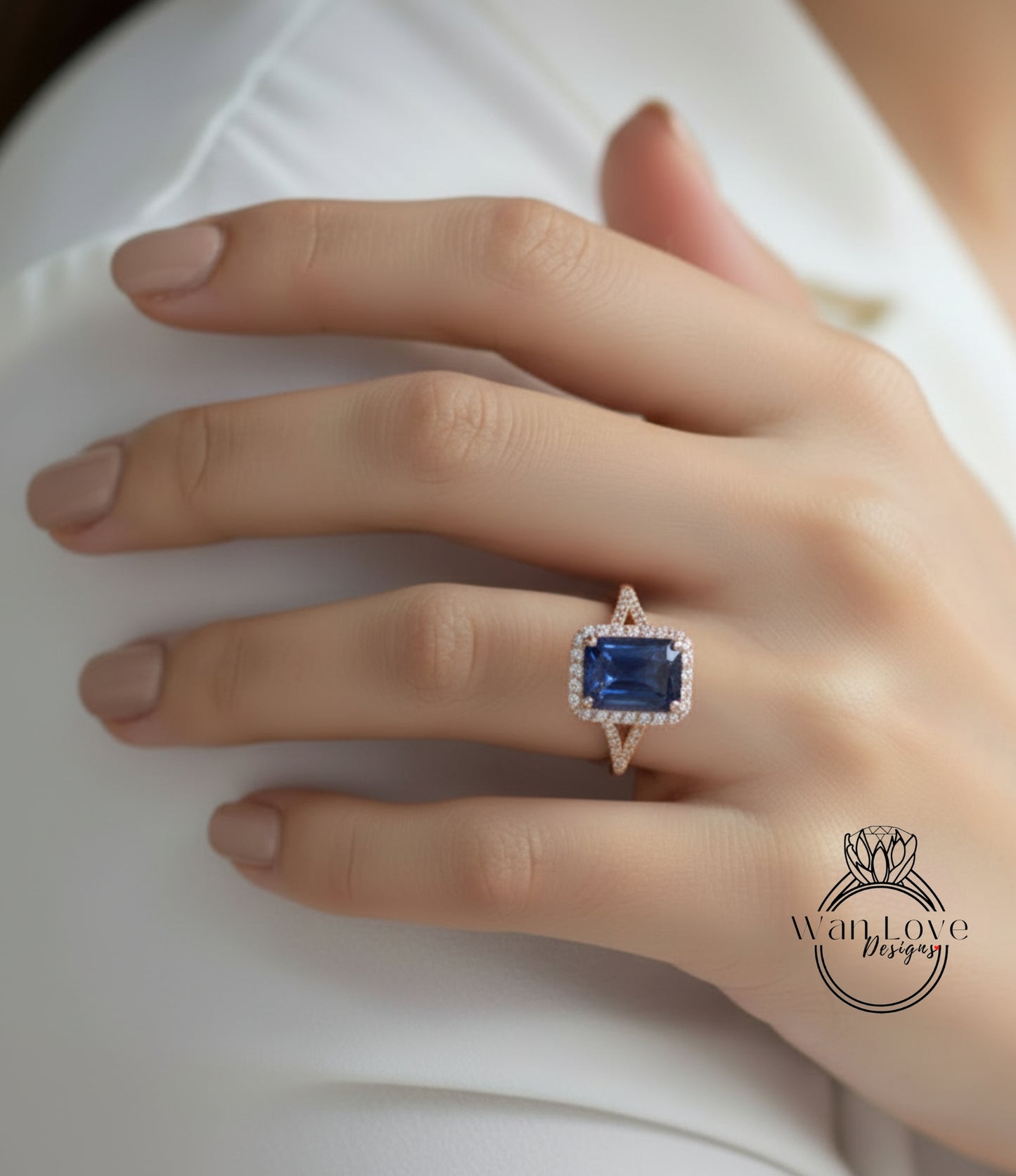 A close-up of a person's hand wearing a ring with a large blue gemstone, likely a sapphire, set in a gold and diamond-encrusted ring.