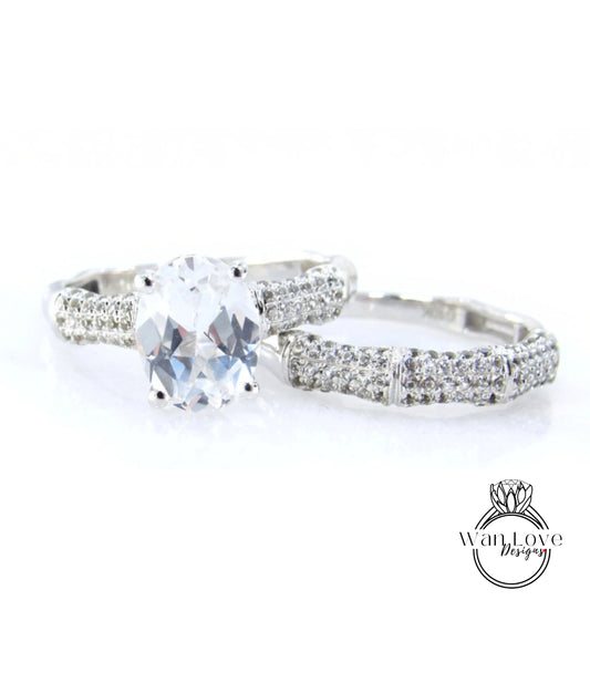 A close-up view of a diamond engagement ring with a large oval-shaped diamond set in a silver band adorned with small diamonds.