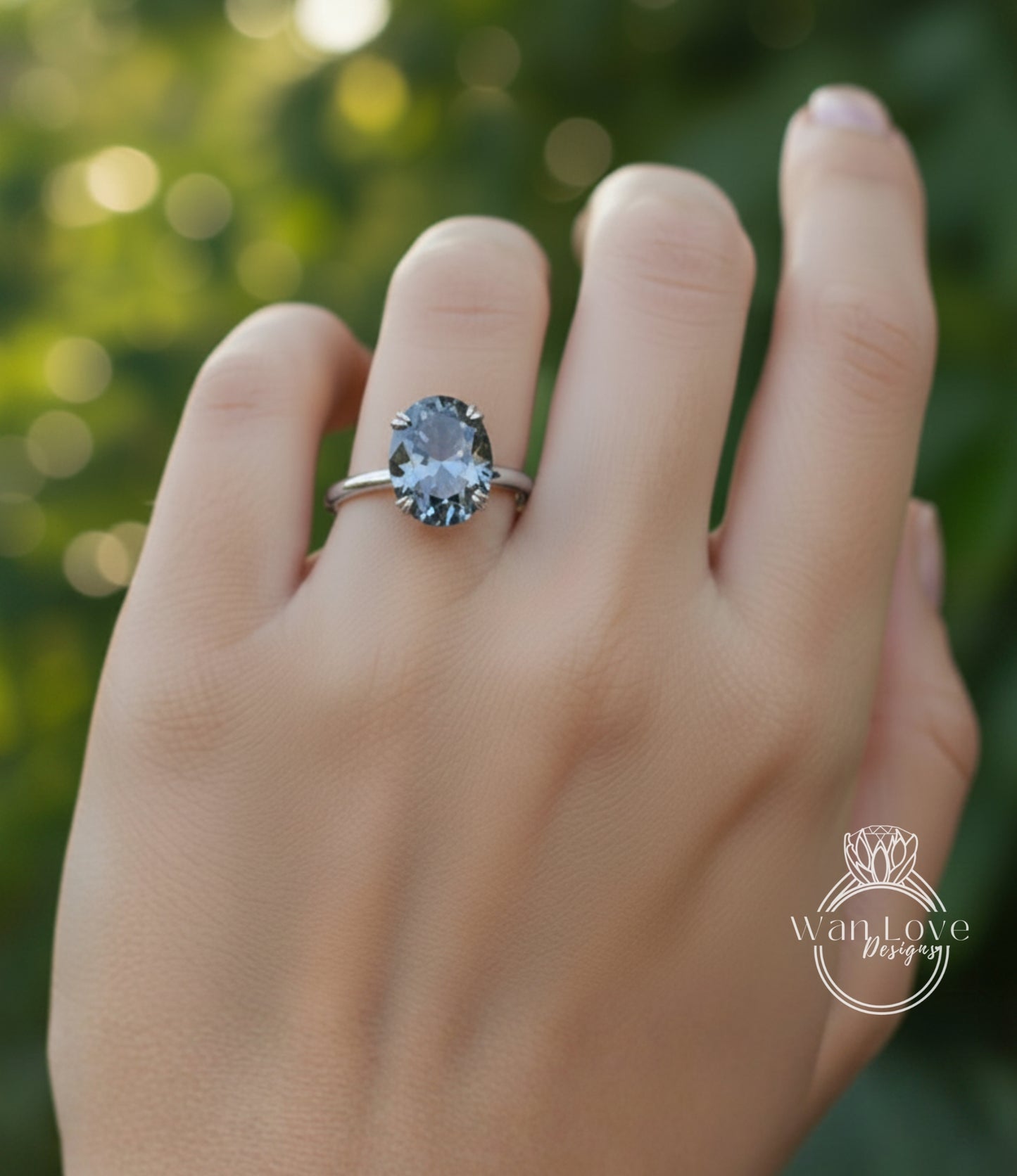 A close-up of a person's hand wearing a ring with a large, dark blue gemstone.
