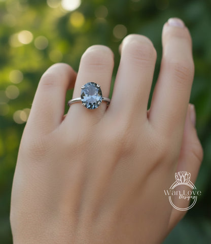 A close-up of a person's hand wearing a ring with a large, dark blue gemstone.