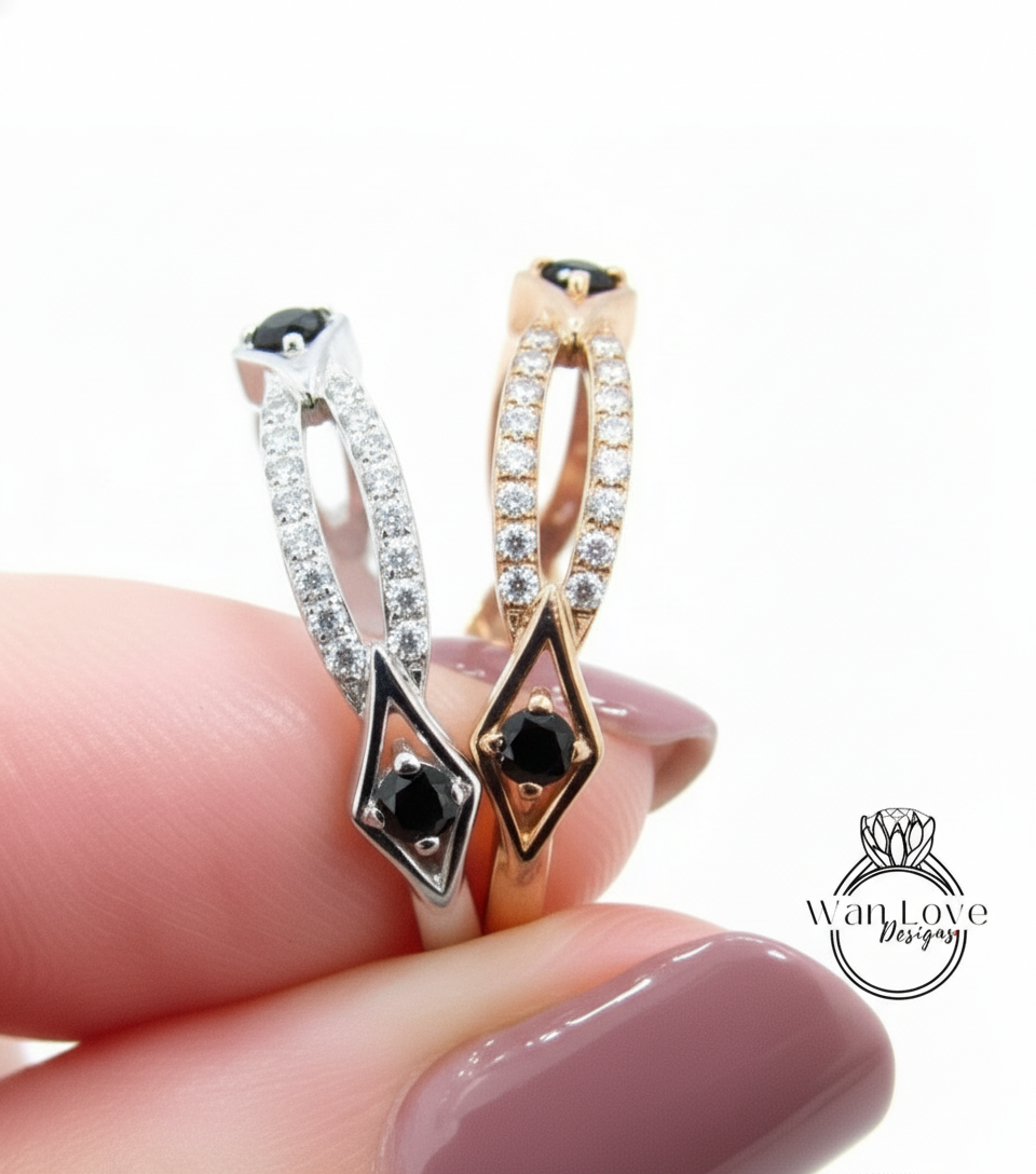 A close-up of a hand holding two rings with gemstones, one silver and one gold.