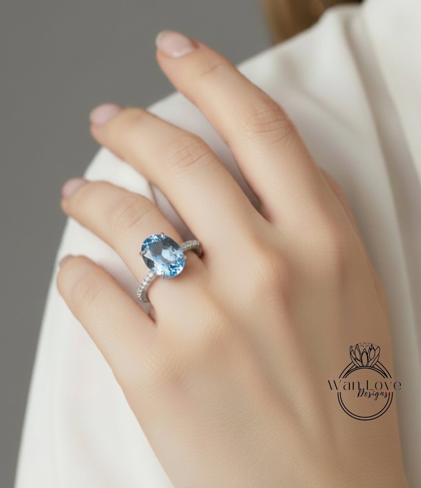 A close-up of a hand wearing a ring with a large blue gemstone, likely an aquamarine or blue topaz stone.