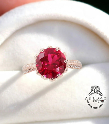A close-up image of a large, vibrant red gemstone set in a gold ring.